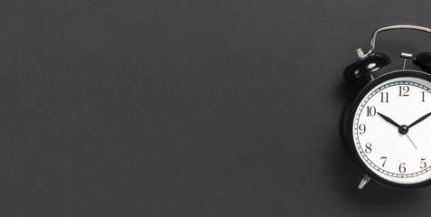 Black retro alarm clock on gray dark background top view Flat lay copy space. Minimalistic...