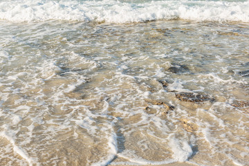 Sandy beach with foamy water and stones