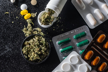 Medical marijuana buds in every first aid kit. pills and cannabis lie on a black background....