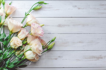 Pink Eustoma flowers on light wooden background. Flat lay, top view. 