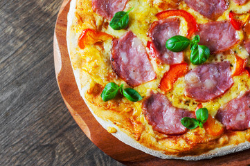 Pizza with Mozzarella cheese, ham, pepper, meat, Tomato sauce, Spices and Fresh Basil. Italian pizza on wooden background