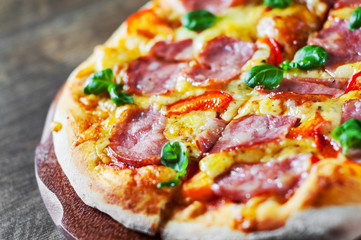 Pizza with Mozzarella cheese, ham, pepper, meat, Tomato sauce, Spices and Fresh Basil. Italian pizza on wooden background