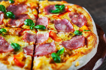 Pizza with Mozzarella cheese, ham, pepper, meat, Tomato sauce, Spices and Fresh Basil. Italian pizza on wooden background
