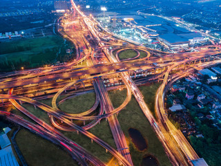 Aerial view over complicate intersection road and express way in Bangkok Thailand at night with long exposure vehicle light trail. Shot by drone.
