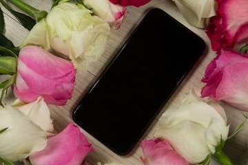Mobile phone surrounded with rose flower