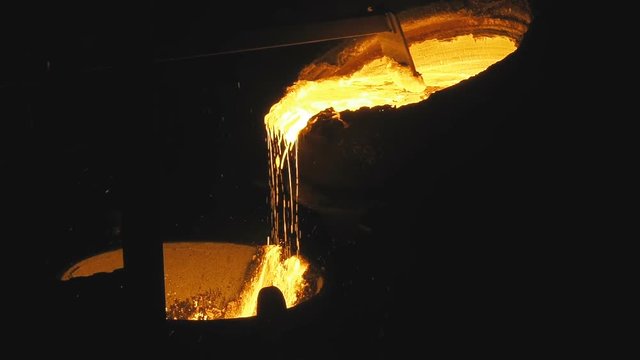 Iron and steel works. Molten metal pouring out of furnace. Liquid metal pour from blast furnace. Molten metal foundry. Pouring molten steel. Liquid steel pouring