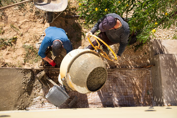 Workers pour concrete solution at a construction site