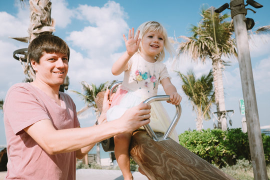Young father holding his little daughter on  a see saw