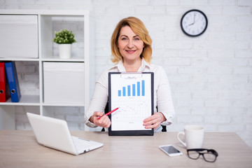 Obraz na płótnie Canvas business plan concept - cheerful mature business woman showing clipboard with charts and graphics