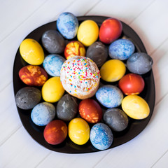 Colored Easter eggs on a black plate painted with natural dyes. Top view