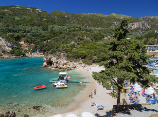 Beautiful beach of Paleokastritsa on Corfu island, Greece. Tourists enjoying a nice summer day on the beach.