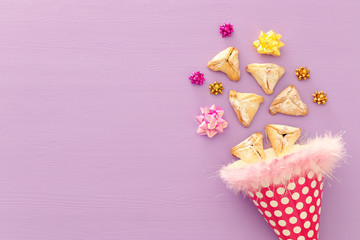 Purim celebration concept (jewish carnival holiday). Traditional hamantaschen cookies over purple wooden table.