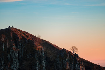 people on the top of a hill at the sunset