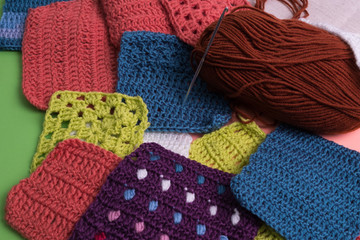 Crochet. Horn of green thread with a crochet. Sample knitting. Crocheted Granny square with wool yarn and crochet hooks. Knitting. Hobby.