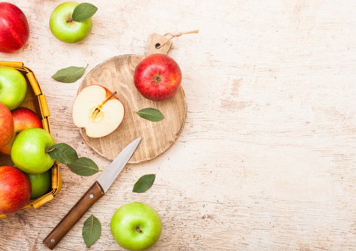 Glass of fresh organic apple juice with red apples on chopping board on wooden background with knife