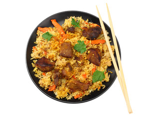 pilaf with meat on black plate isolated on white background. top view