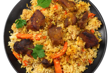 pilaf with meat on black plate isolated on white background. top view
