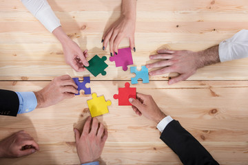 Business people join puzzle pieces in office. Concept of teamwork and partnership