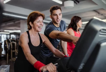 Foto op Canvas Two cheerful female seniors in gym with a young trainer doing cardio work out. © Halfpoint