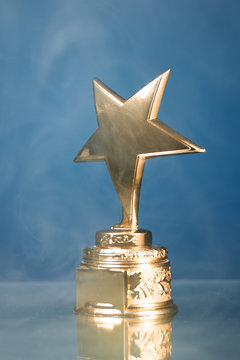 gold star trophy in smoke, blue background