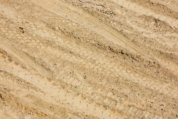 Traces of tire treads on a dry soil surface.