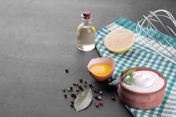 Mayonnaise in a wooden bowl and ingredients for making mayonnaise on a black background. white sauce. with space for text