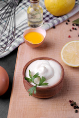 Mayonnaise in a wooden bowl and ingredients for making mayonnaise on a cutting board. white sauce. close-up