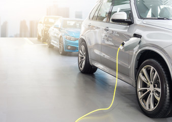 EV Car or Electric car at charging station with the power cable supply plugged in on blurred city...