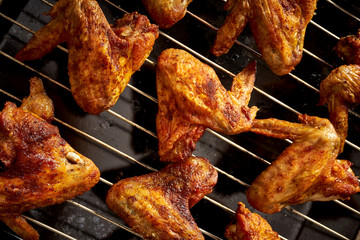 Delicious hot grilled chicken wings on grid grill.