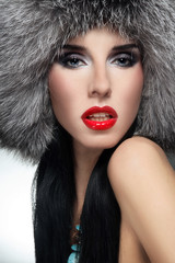 Portrait of young beautiful sexy woman with red lipstick in fur hat