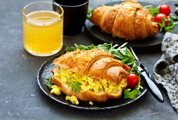 Breakfast of croissant with scrambled eggs and salad.
