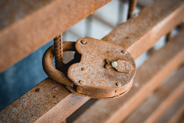 Close-up metal corrosion of an old rusty lock in the open air under the influence of water and air on a rusty iron fence. Vintage item.