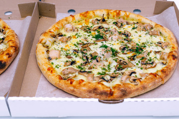 Two pizzas in a cardboard box on a light background. Top view. Pizza delivery. Pizza menu. Pizza on the kitchen table.