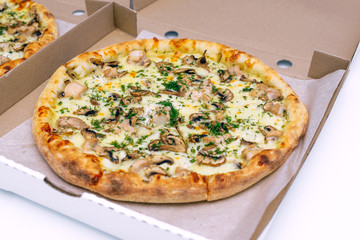 Two pizzas in a cardboard box on a light background. Top view. Pizza delivery. Pizza menu. Pizza on the kitchen table.