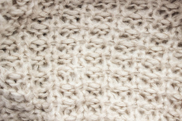 Knitted texture of beige wool threads close-up.
