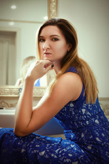 Model is posing in a bathroom wearing blue dress