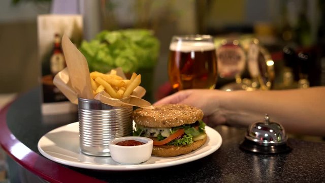 Hamburger, chips,  beer, ketchup. The waitress serves. Lunch in a restaurant. Traditional Latvian food. Riga Latvia. 4K
