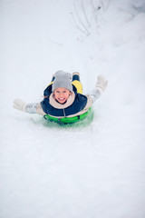 Adorable little happy girl sledding in winter snowy day.