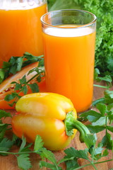 Carrot juice with greens on a wooden board