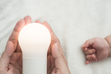 Light bulb in mother hand and baby hand: concept of idea for kid