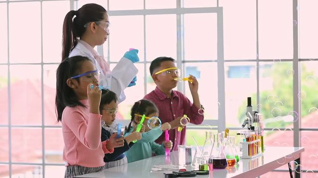 Slow motion scene of Asian teacher and students in laboratory room, they blowing bubbles, colorful test tubes on table in laboratory room, concept for fun in laboratory room.