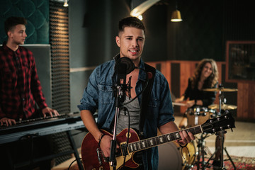 Music band having rehearsal in a studio