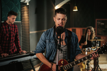 Music band having rehearsal in a studio