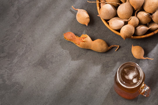 Tamarind juice in a glass surrounded by fresh ripe tamarinds - Tamarindus indica