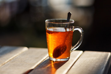 Sochi, Russia. Glass mug with a metal spoon, filled with tea and lemon stands on a wooden table. Waterfront cafe
