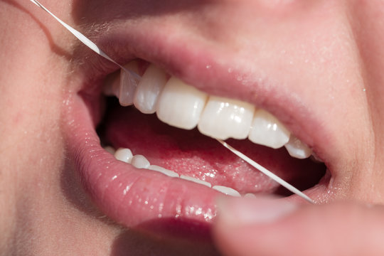 Mund einer jungen Frau, die Zahnseide anwendet