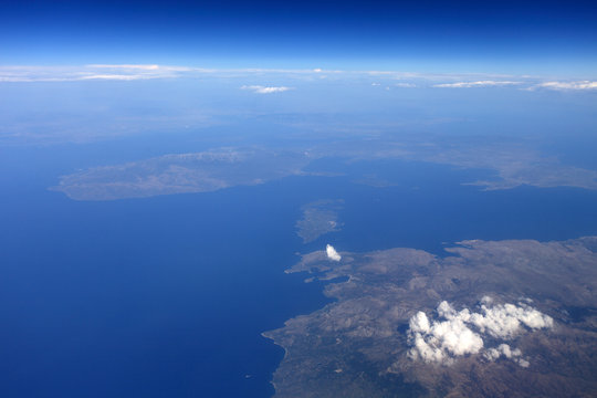 View from a flying plane in the sky to the islands in the ocean through the clouds