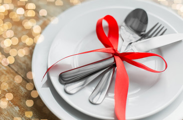 valentines day, table setting and festive dinner concept - close up of plate with spoon, knife and...