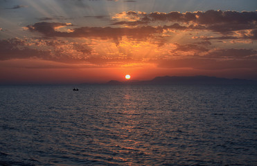 Fototapeta premium Beautiful view of the sea at sunset, the sun on the horizon and the rays in the clouds
