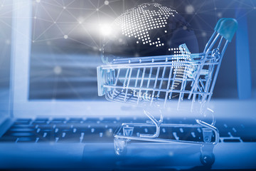 Online shopping concept. Closeup of shopping basket with digital globe and wireless digital line connection symbol on laptop. Business and technology.